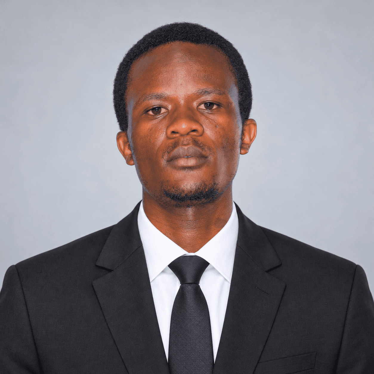 Professional portrait of Ogira Mark Orinda in a black blazer, white shirt and dark tie